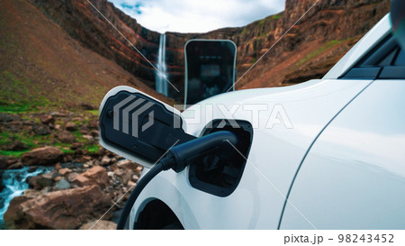 Progressive concept of energy sustainability by EV car in the waterfall. Progressive concept of energy sustainability by EV car in the waterfall. 98243452