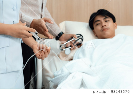 Doctor and nurse inject medicine, dosage into IV tube in sterile recovery room Doctor and nurse inject medicine, dosage into IV tube in sterile recovery room 98243576