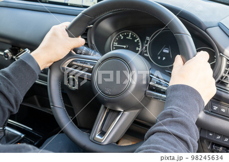 車を運転する男性の手元 98245634