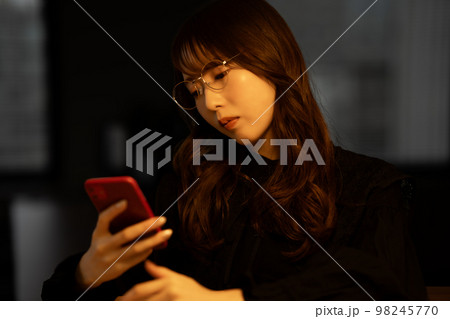 残業中にスマホを使う女性 残業中にスマホを使う女性 98245770