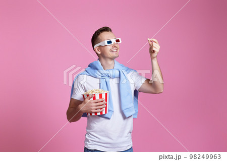 Young caucasian man in 3d glasses eating popcorn 98249963