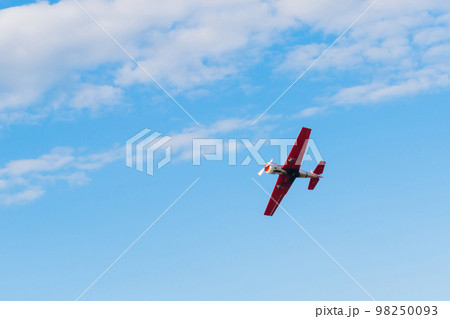 Light aircraft flying in blue sky and doing stunts 98250093