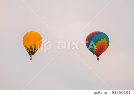 Two hot air balloons flying against grey sky at Winter aerostat festival 98250101