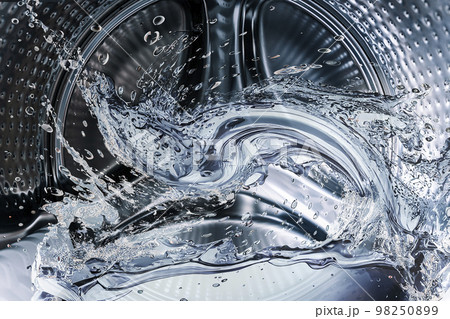 Washing machine drum with clean water flow and splashes. Laundry, washing powder concept. 98250899