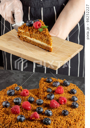 A female chef bakes and eats a piece of homemade carrot cake on a dark background 98252227