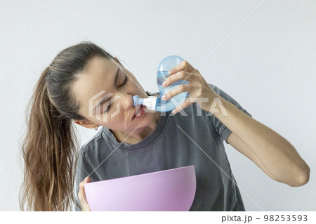Nasal irrigation. A young girl uses the Neti Pot to treat her runny nose and colds. Nasal lavage, irrigation therapy. 98253593