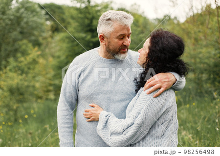 Close up romantic couple standing in autumn park and hugging in daytime. Man and woman wearing blue sweaters. Woman is brunette and man is gray. Close up romantic couple standing in autumn park and hugging in daytime. Man and woman wearing blue sweaters. Woman is brunette and man is gray. 98256498