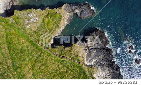 Grassy cliffs on the Atlantic Ocean coast. Landscape of Ireland from a height. Seaside rocks. 98256583