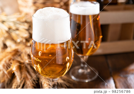 Glass of light craft beer on a wooden table. Beer is poured into a glass with foam and bubbles. Glass of light craft beer on a wooden table. Beer is poured into a glass with foam and bubbles. 98256786