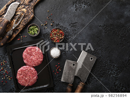 Sealed vacuum tray with two raw beef burgers with cleaver and barbeque fork and knife Sealed vacuum tray with two raw beef burgers with cleaver and barbeque fork and knife 98256894