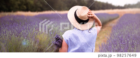 Young woman a hat with a bouquet of lavender in field Young woman a hat with a bouquet of lavender in field 98257649