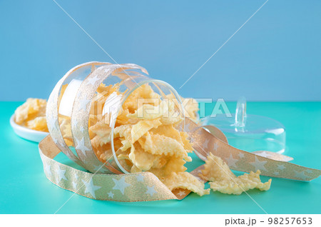 Sfrappole or chiachiere or angel wings on a bright blue background. Italian Carnival and TYPICAL Sfrappole or chiachiere or angel wings on a bright blue background. Italian Carnival and TYPICAL 98257653