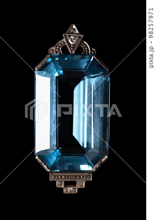 Emerald cut aquamarine, in octagon shape, set in a detailed Art Deco style silver necklace pendant, with two small diamonds. Close-up, isolated, from above, on black background, macro photo. Emerald cut aquamarine, in octagon shape, set in a detailed Art Deco style silver necklace pendant, with two small diamonds. Close-up, isolated, from above, on black background, macro photo. 98257971