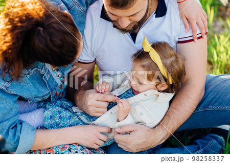 top view. a little daughter in the arms of mom and dad on a lawn. family picnic 98258337