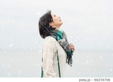 雪が降る冬の海に出かける女性 98259706