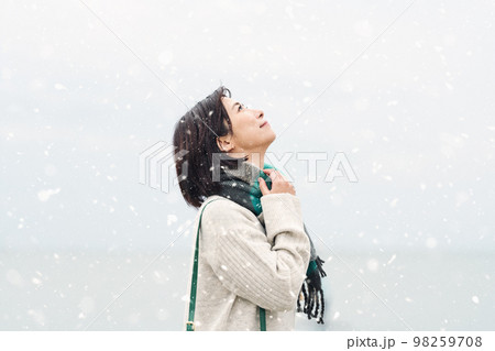 雪が降る冬の海に出かける女性 雪が降る冬の海に出かける女性 98259708