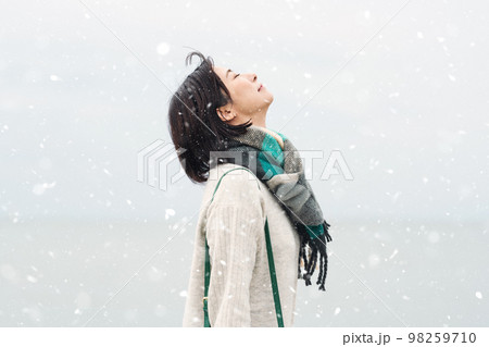 雪が降る冬の海に出かける女性 98259710