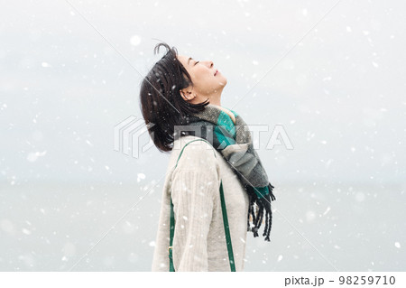 雪が降る冬の海に出かける女性 雪が降る冬の海に出かける女性 98259710