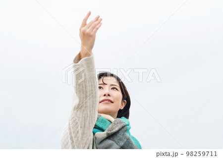 空に向かって手を伸ばす女性 空に向かって手を伸ばす女性 98259711