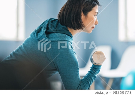 ジムで鉄アレイを使ってトレーニングをする女性 ジムで鉄アレイを使ってトレーニングをする女性 98259773