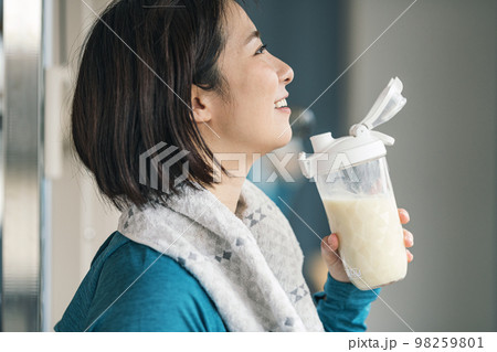 スポーツジムで筋トレ後にプロテインを飲む女性 98259801