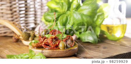 Dried tomatoes with herbs and olive oil. Traditional canned tomatoes in Italy. Ingredients for Dried tomatoes with herbs and olive oil. Traditional canned tomatoes in Italy. Ingredients for 98259929