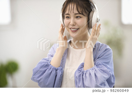 ヘッドフォンで音楽を聴く若い女性 98260849
