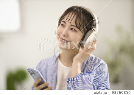 ヘッドフォンで音楽を聴く若い女性 98260850