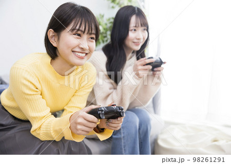 友達と2人でTVゲームをする若い女性 98261291