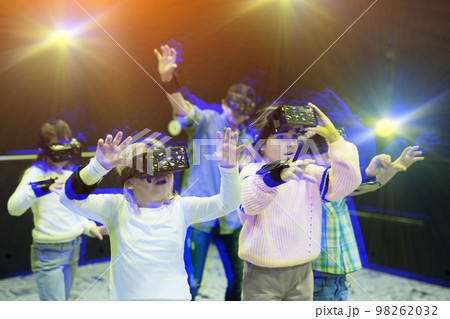 Enthusiastic cheerful smiling children in virtual reality glasses in quest room Enthusiastic cheerful smiling children in virtual reality glasses in quest room 98262032