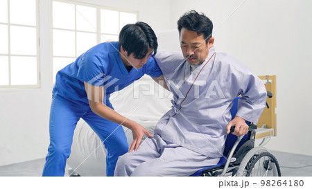 ベッドから車椅子へ移乗介助する介護士 98264180