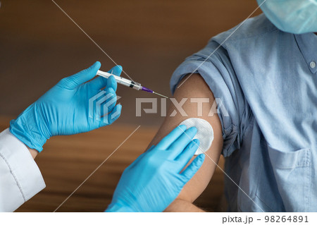 Unrecognizable Nurse Holding Syringe, Making Vaccine Shot To Male Patient Unrecognizable Nurse Holding Syringe, Making Vaccine Shot To Male Patient 98264891