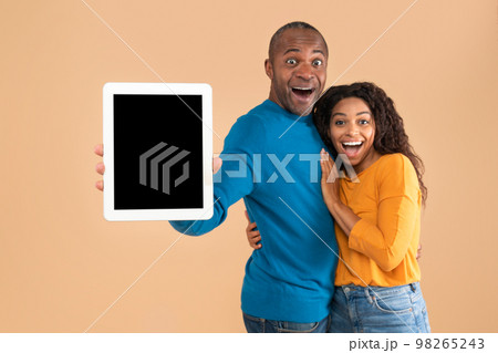 Happy black spouses showing digital tablet with black screen, family recommending new app or cool website, mockup 98265243