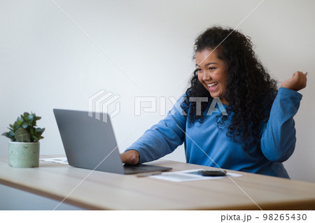 Emotional happy plus size young woman working from home Emotional happy plus size young woman working from home 98265430
