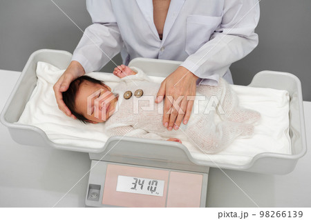 newborn baby weight measurement on digital scales with doctor in hospital 98266139