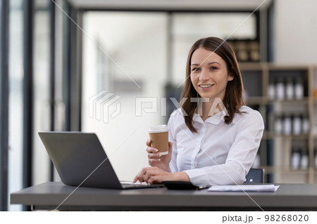 Portrait confident businesswoman working on laptop at her workplace at modern office. Portrait confident businesswoman working on laptop at her workplace at modern office. 98268020