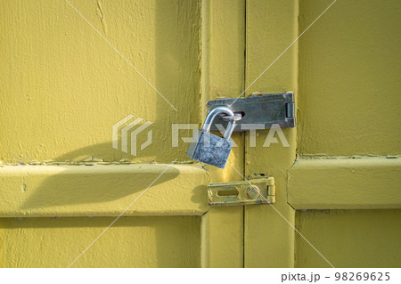 Yellow wood door closed with padlock. 98269625