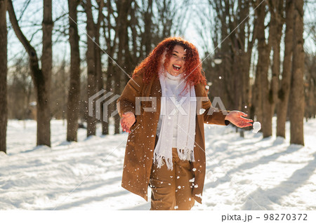 Fat caucasian woman playing snowballs in the park.  98270372