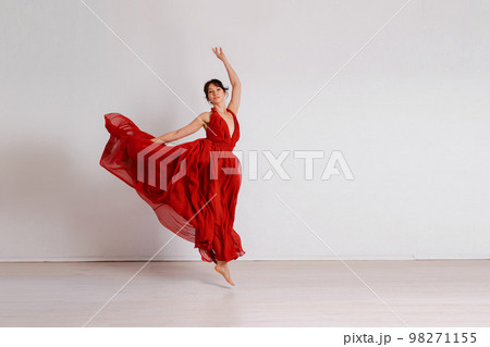 Dancer in a red flying dress. Woman ballerina dancing on a white studio background 98271155
