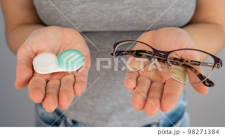 A woman makes a choice between lenses and glasses. A woman makes a choice between lenses and glasses. 98271384