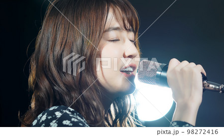 スポットライトを浴びて歌う女性　ライブ　コンサート　カラオケ 98272416