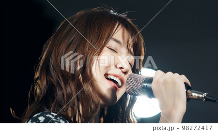 スポットライトを浴びて歌う女性　ライブ　コンサート　カラオケ 98272417