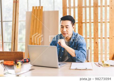 Middle age adult asian man carpenter using laptop for online working with customer wotk at home 98273094