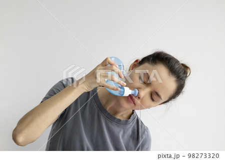 Girl rinses her nose with saline solution at home Using Neti Pot. Treatment and prevention of colds. How to rinse your nose when you have a runny nose. 98273320