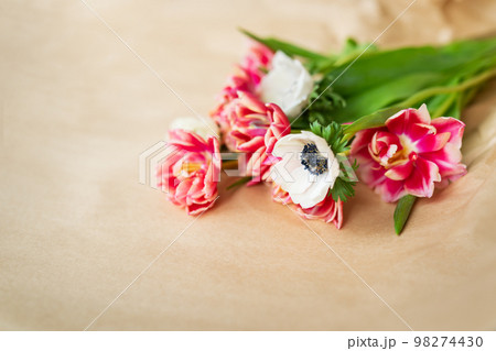 Beautiful red and white bouquet of tulips and anemones in kraft paper. The concept of spring and flowering. With copy space. Beautiful red and white bouquet of tulips and anemones in kraft paper. The concept of spring and flowering. With copy space. 98274430