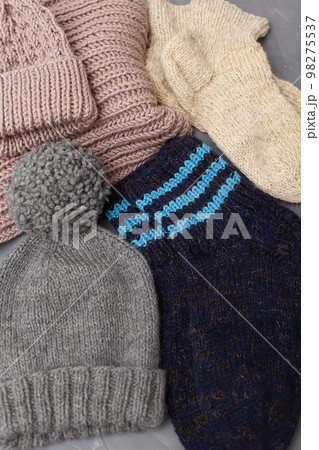 Woolen knitted clothing, wool cap, mittens and scarf. Warm womans winter clothes on white wooden background. Top view. Copy space. Flat lay Woolen knitted clothing, wool cap, mittens and scarf. Warm womans winter clothes on white wooden background. Top view. Copy space. Flat lay 98275537