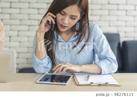 Asian women talk via smartphone work from home small office desk. Young asian Woman hands holding phone technology lifestyle. Happy Women person calling use digital smart phone working home office 98276115