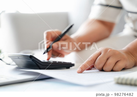 Woman is calculating annual tax with calculator and filling form of Individual Income Tax Return. Season to pay Tax and Budget planning concept. Woman is calculating annual tax with calculator and filling form of Individual Income Tax Return. Season to pay Tax and Budget planning concept. 98276482