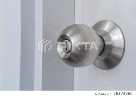Close-up of a silver doorknob mounted on a white door. 98278960