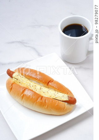 あらびきソーセージにマスタードをたっぷりかけた惣菜パンとコーヒー 98279077